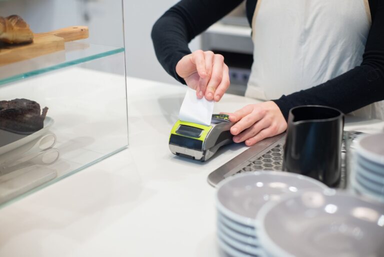 Culpa Inkasso Erfahrungen – Close-up of a cashless transaction at a modern café counter with hands holding a receipt.